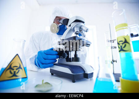 Male scientist in protective clothing working with microscope in laboratory Stock Photo