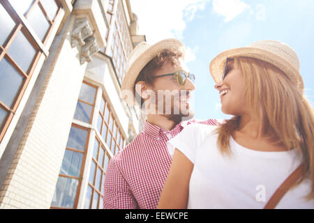 Happy couple in hats and sunglasses looking at one another Stock Photo