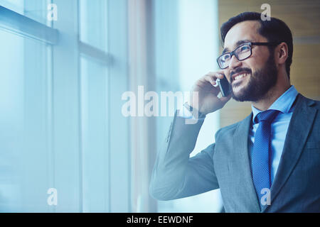 Smiling businessman in eyeglasses talking on the phone Stock Photo