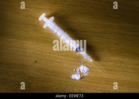 Drug syringe and cooked heroin on wood table Stock Photo