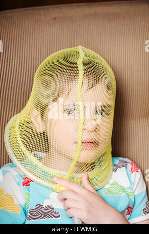 Portrait of girl with net covering her face. She looks troubled and pensive Conceptual image of childhood boredom, contemplation Stock Photo