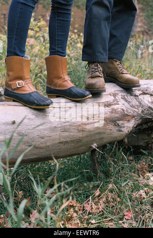 Close up of couple standing side by side on a tree trunk. Stock Photo