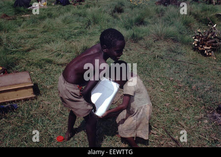 Refugee children arriving in Burundi from Rwanda drink water from Jerry can circa 1994 Stock Photo