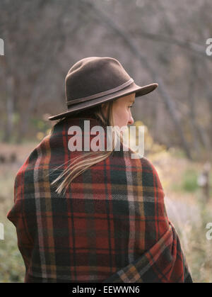 Young blond woman wearing a hat, wrapped in a blanket. Stock Photo