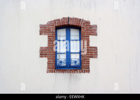 Blue metal Window frame edged with bricks on white House in Brittany, France Stock Photo