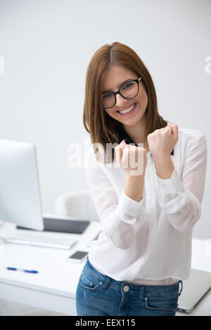 Happy business woman keeping arms raised in office Stock Photo