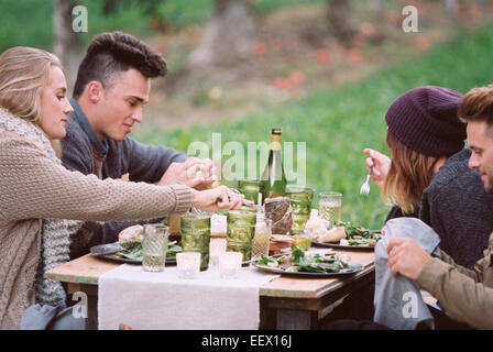 Apple orchard. Group of people sitting on ground Stock Photo