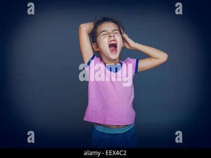 teen girl yawns wants to sleep on a gray background cross proces Stock Photo