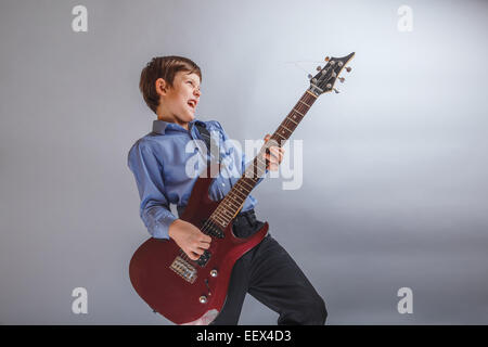 teenager boy brown hair European appearance playing guitar, happ Stock Photo