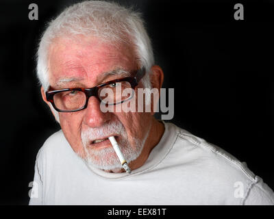 Elderly man smoking a cigarette with an angry and upset look on his face Stock Photo