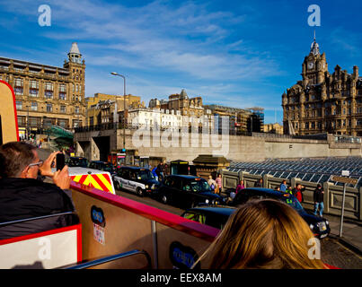 View of tourist on open top bus taking photographs near Waverley Station on tour of Edinburgh city centre Scotland UK Stock Photo