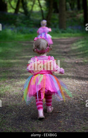 Two little girls walking along a path in springtime woodland. Stock Photo