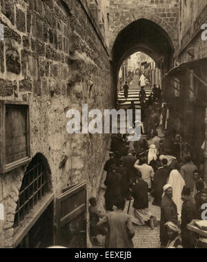 Via Dolorosa - Jerusalem. Pilgrims at station - People kneeling in a narrow street, circa 1913 Stock Photo