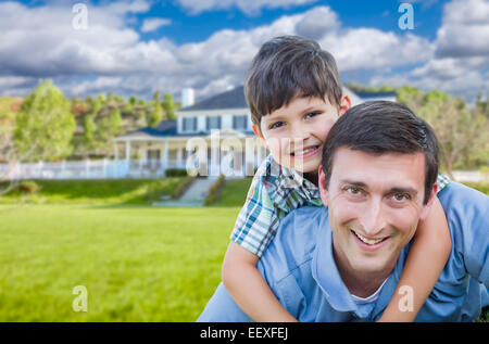 Mixed Race Father and Son Playing Piggyback in Front of Their House. Stock Photo