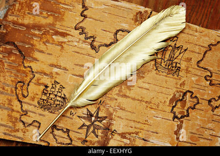 Gold quill pen on unusual sea map with ships on the order of olden time on birchbark Stock Photo