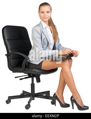 Businesswoman on office chair, holding closed laptop Stock Photo