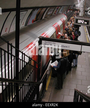Commuters reading papers waiting on the platform for a Tube train during the morning rush hour at Clapham Common Underground station, London, UK. Stock Photo