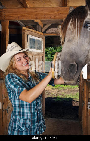 Woman in a stable with a horse Stock Photo