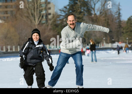 Father and son ice skating outdoors Stock Photo