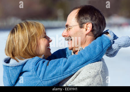 Couple on ice skates hugging outdoors in winter Stock Photo