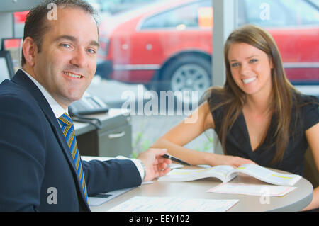 Woman sitting in office at car dealership Stock Photo