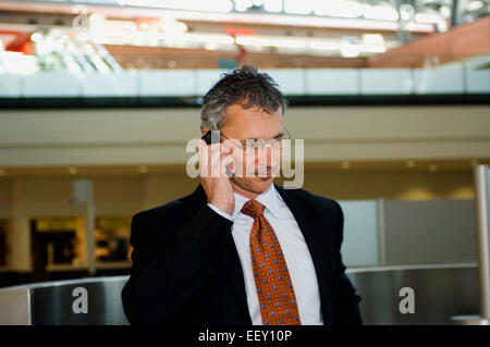 Businessman in airport using personal digital assistant Stock Photo