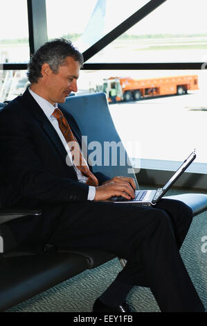 Businessman in airport using laptop Stock Photo