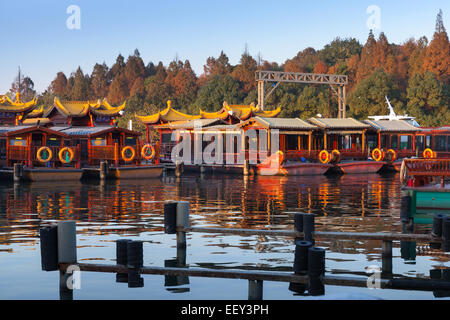 Traditional Chinese wooden recreation boats are moored on the West Lake coast. Famous park in Hangzhou city, China Stock Photo
