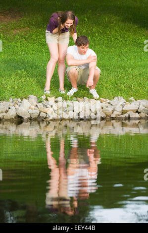 Two people at a park pointing at something in the water Stock Photo