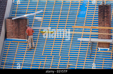 Builder on a steep roof on building without any safety equipment Stock Photo