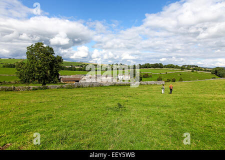 2 people walking under blue skys and white clouds in summer near to Meadow Place Grange Over Haddon Derbyshire England UK Stock Photo