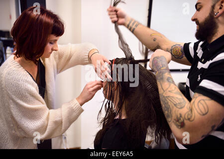 Student hairstylist and makeup artist working on hair and face of a model in a salon Stock Photo