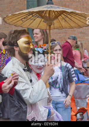People wearing colorful costumes, a parasol, masks and expressions walk in the Spring Mardi Gras parade Stock Photo
