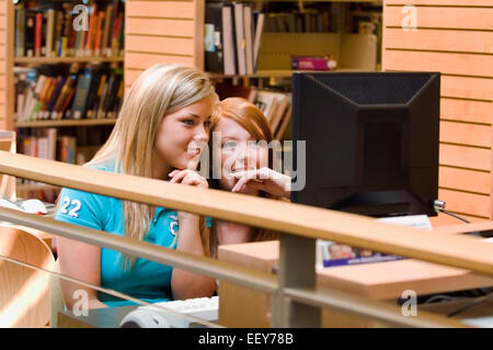Young adults in a library using a computer terminal Stock Photo