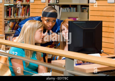 Young adults in a library using a computer terminal Stock Photo