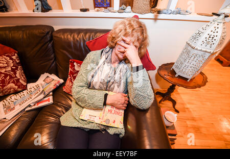 Tired mature woman falling asleep on the sofa at home Stock Photo