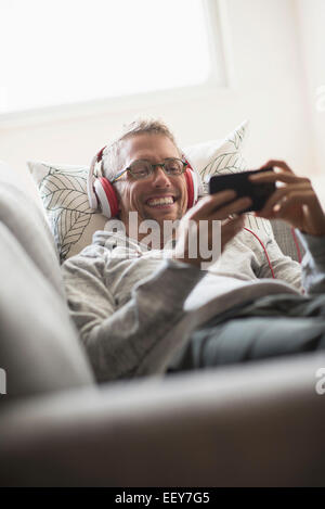 Man lying on sofa listening to music Stock Photo