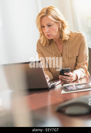 Business woman using laptop and cell phone Stock Photo