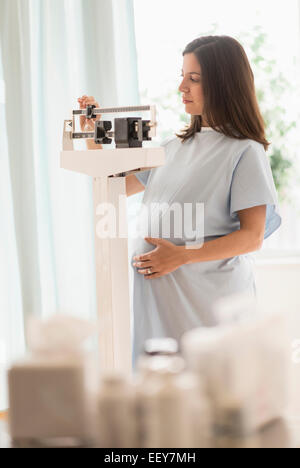 Pregnant woman in doctors office standing on scale Stock Photo