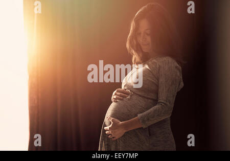 Pregnant woman touching belly at home Stock Photo