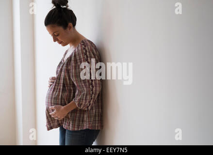 Pregnant woman leaning against wall Stock Photo