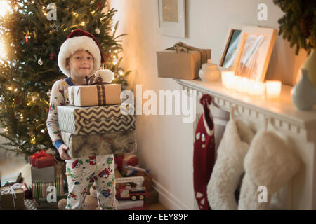 Portrait of boy (6-7) wearing santa claus hat and carrying presents Stock Photo