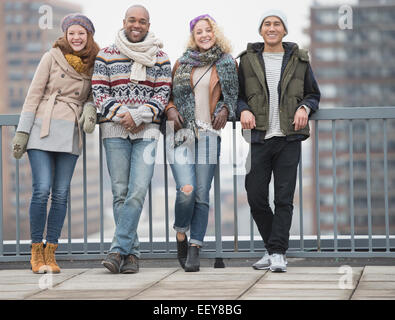 Portrait of happy friends leaning against bridge railing Stock Photo