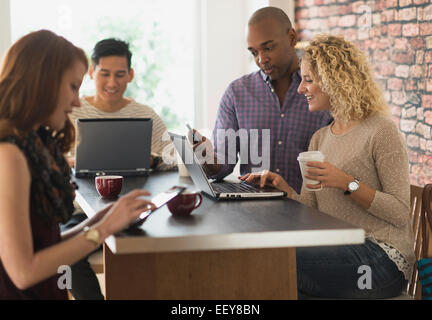 Friends sitting in cafe, using laptops and digital tablets Stock Photo