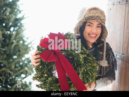 Portrait of young woman holding Christmas wreath Stock Photo