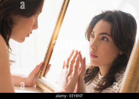 Serious young woman looking into mirror Stock Photo