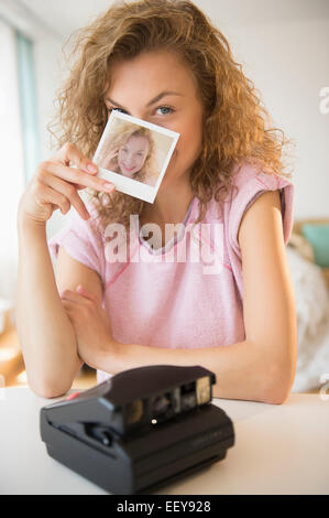 Young woman holding Polaroid photo in front of her face Stock Photo