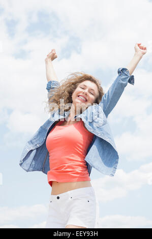 Portrait of young woman with arms raised Stock Photo