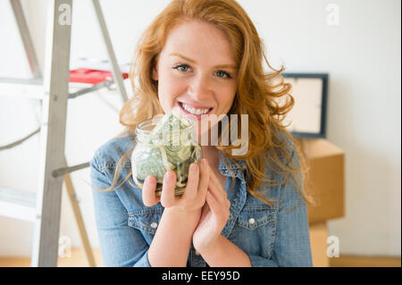 Portrait of woman holding jar with money Stock Photo
