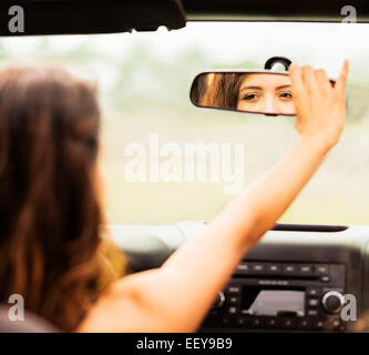Reflection of young woman in rear view mirror Stock Photo